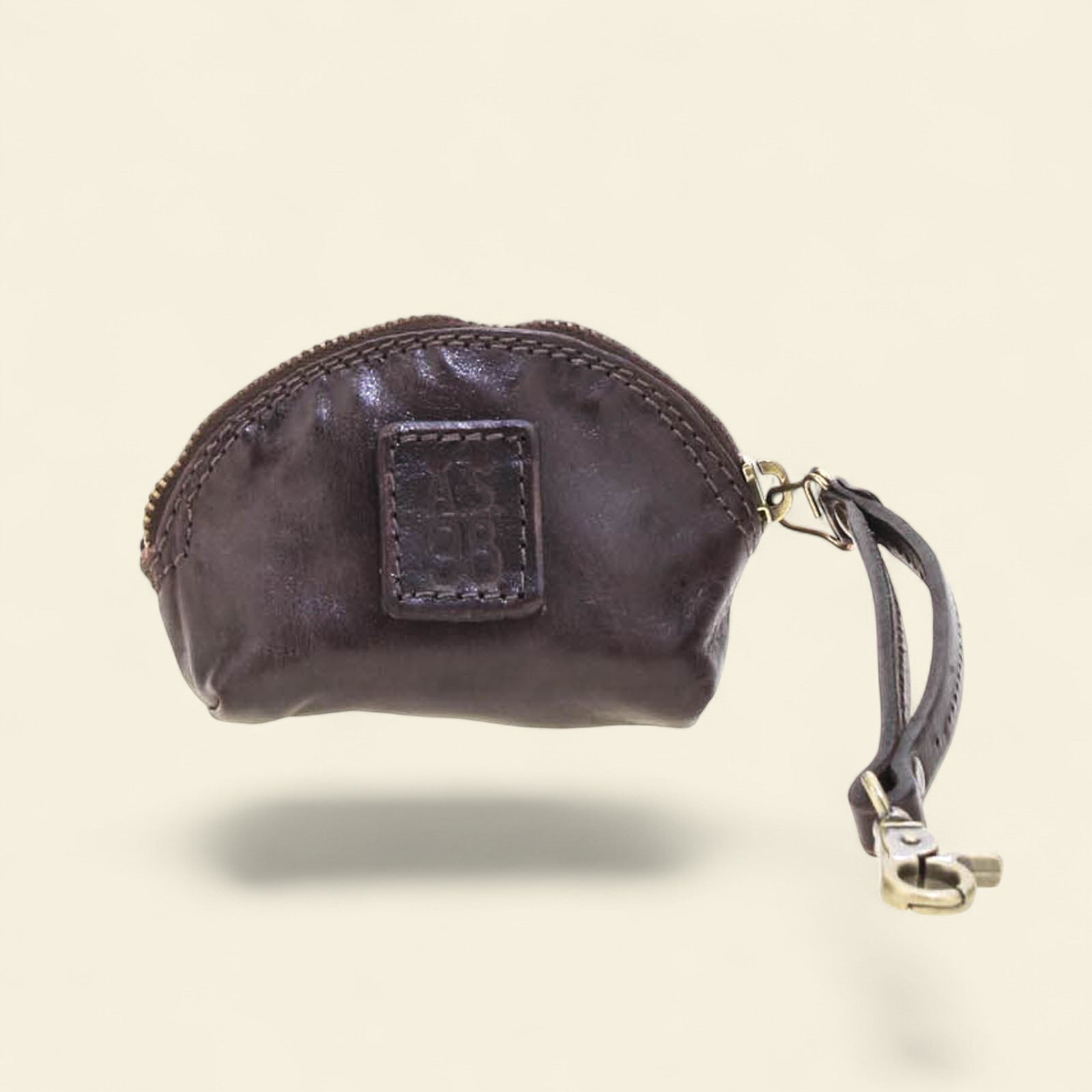 Black leather coin purse with a visible brand logo on a beige background