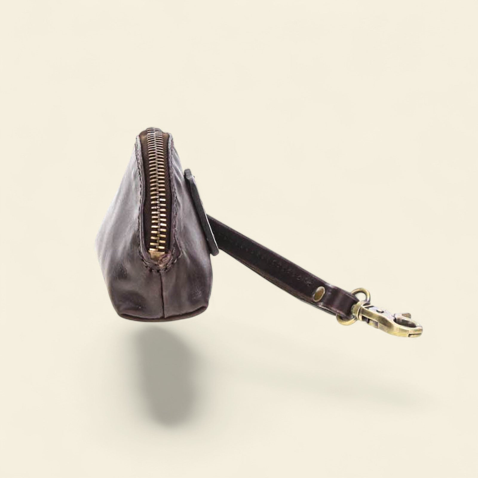 Black leather coin purse with a visible brand logo on a beige background