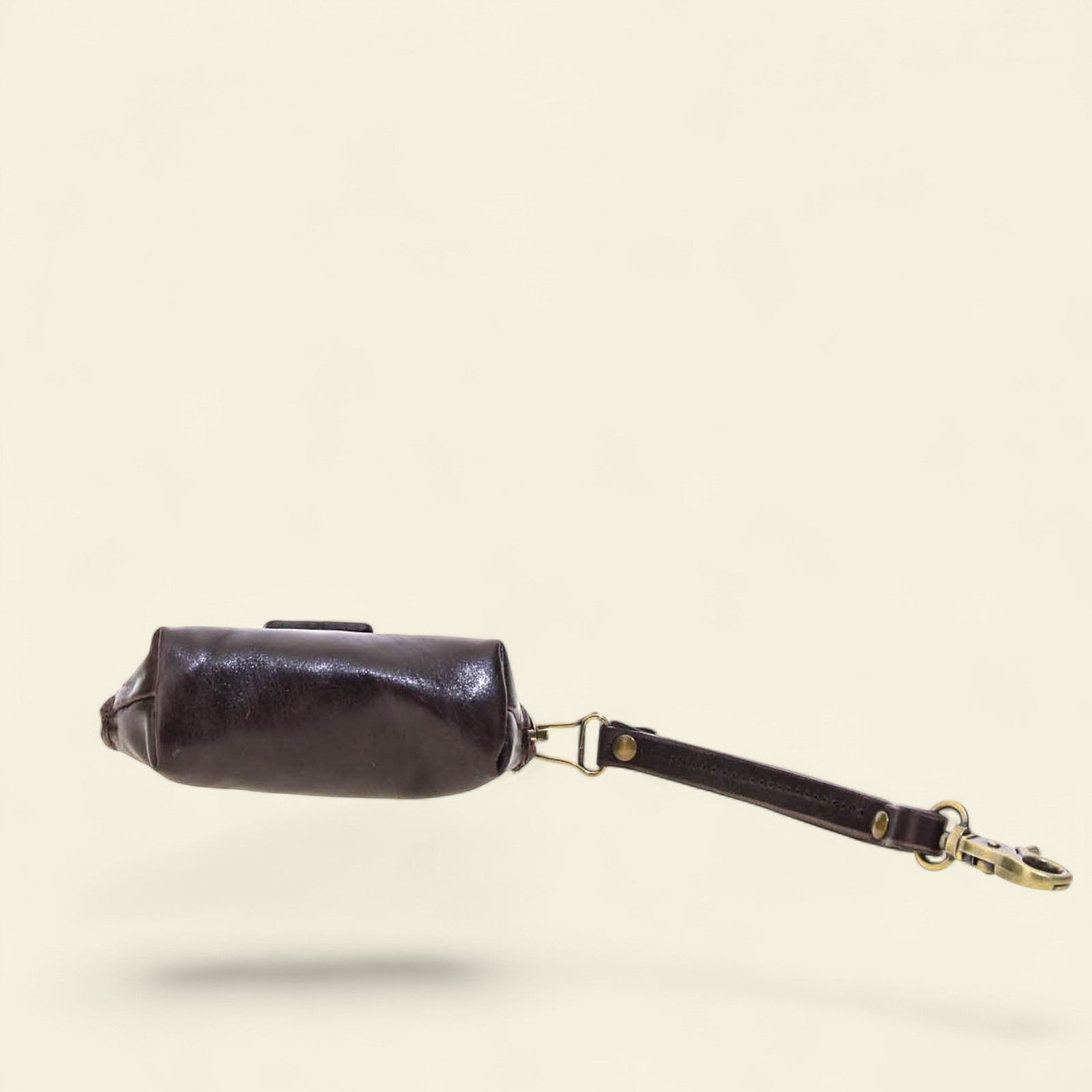 Black leather coin purse with a visible brand logo on a beige background