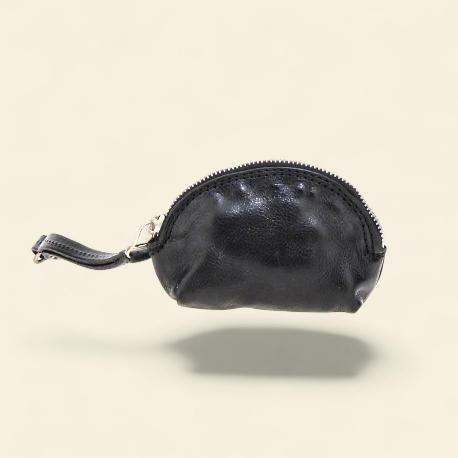 Black leather coin purse with a visible brand logo on a beige background
