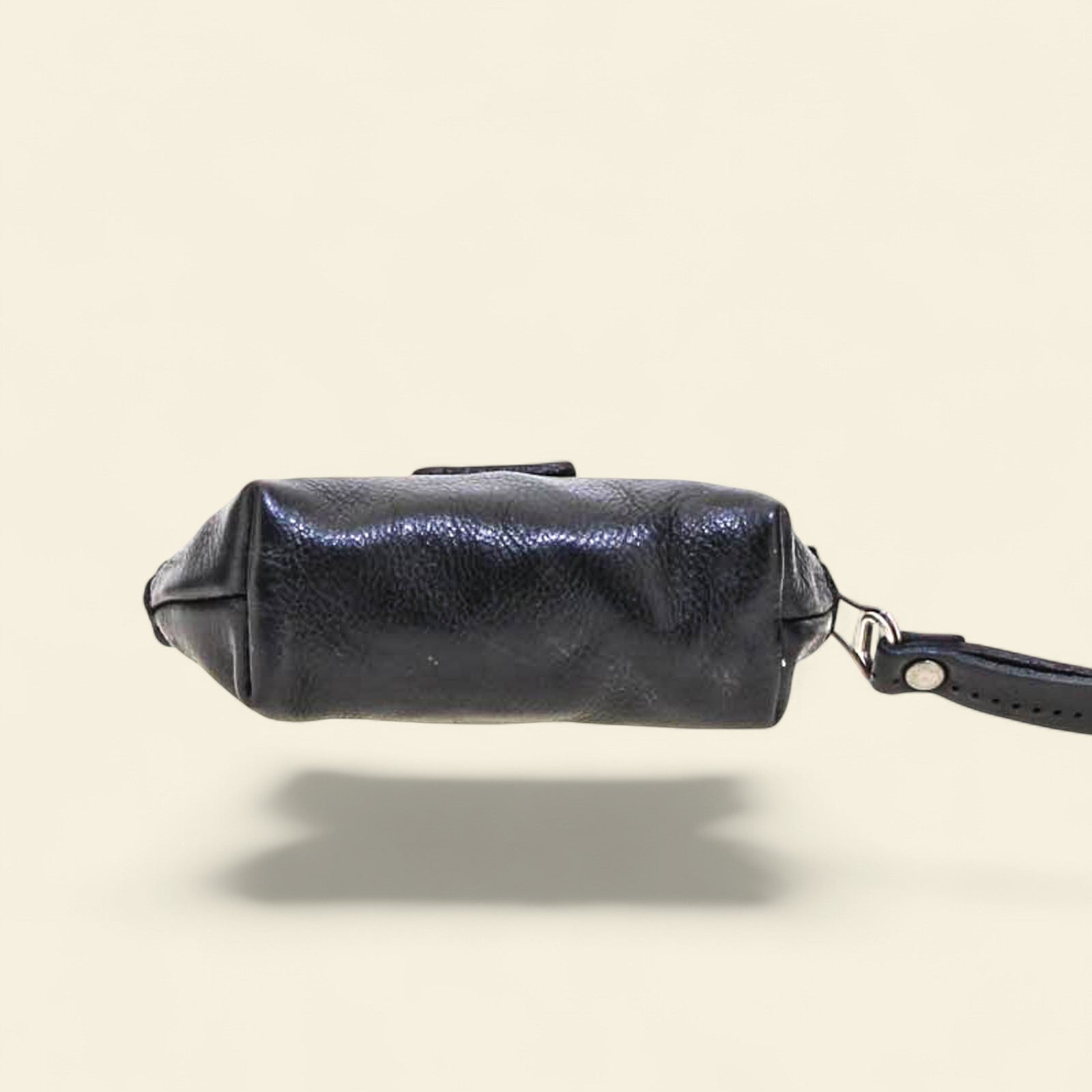 Black leather coin purse with a visible brand logo on a beige background