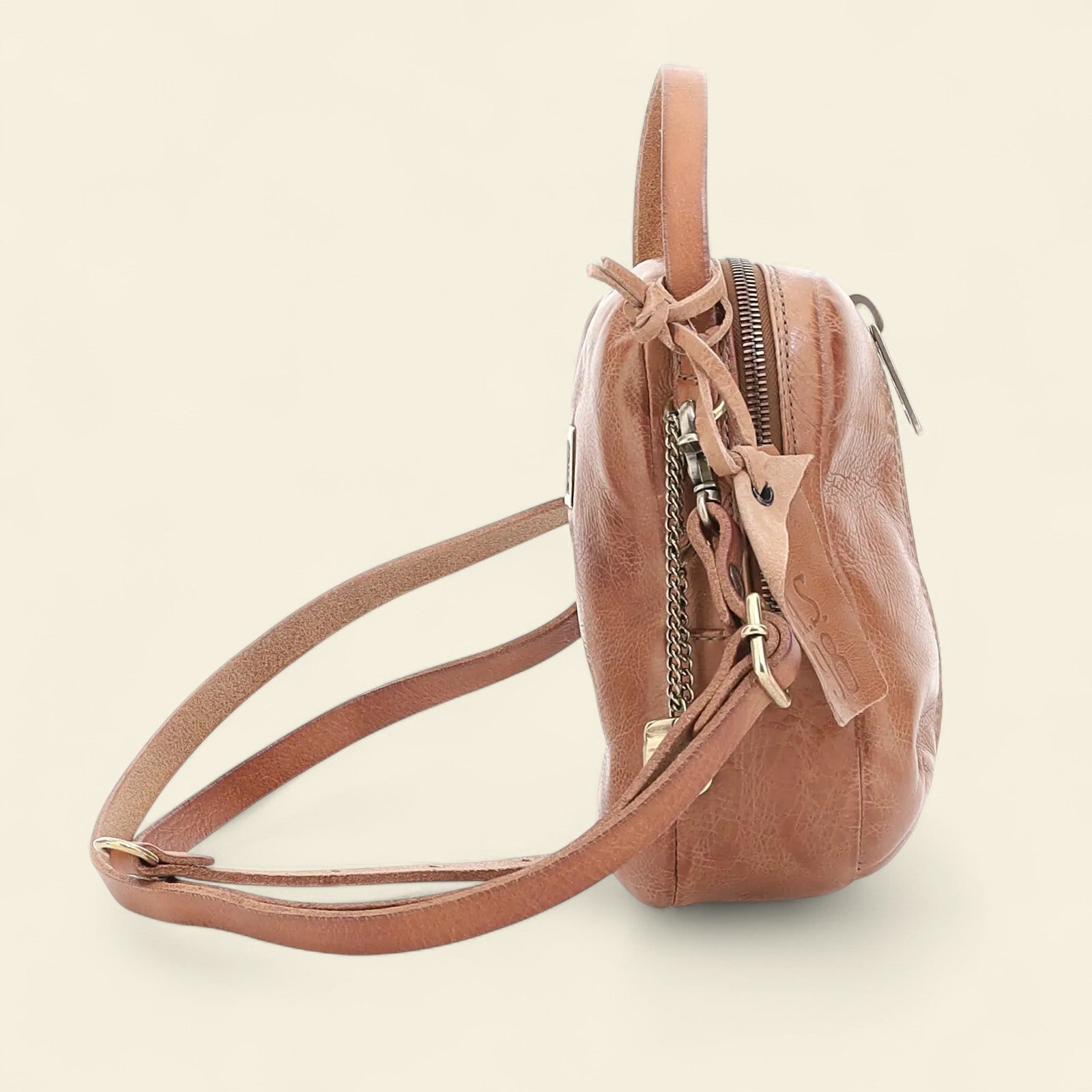 Brown leather crossbody bag on a beige background