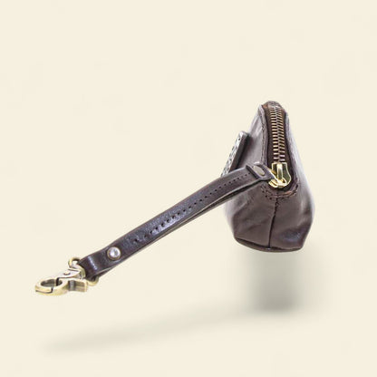 Black leather coin purse with a visible brand logo on a beige background 