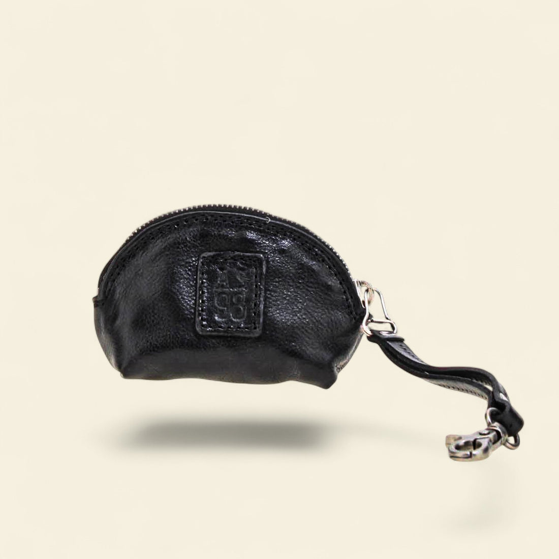 Black leather coin purse with a visible brand logo on a beige background 