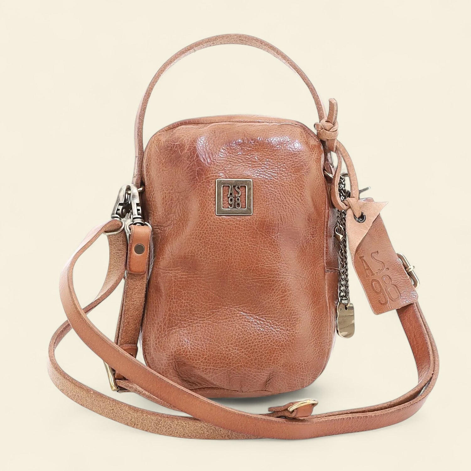 Brown leather crossbody bag on a beige background 
