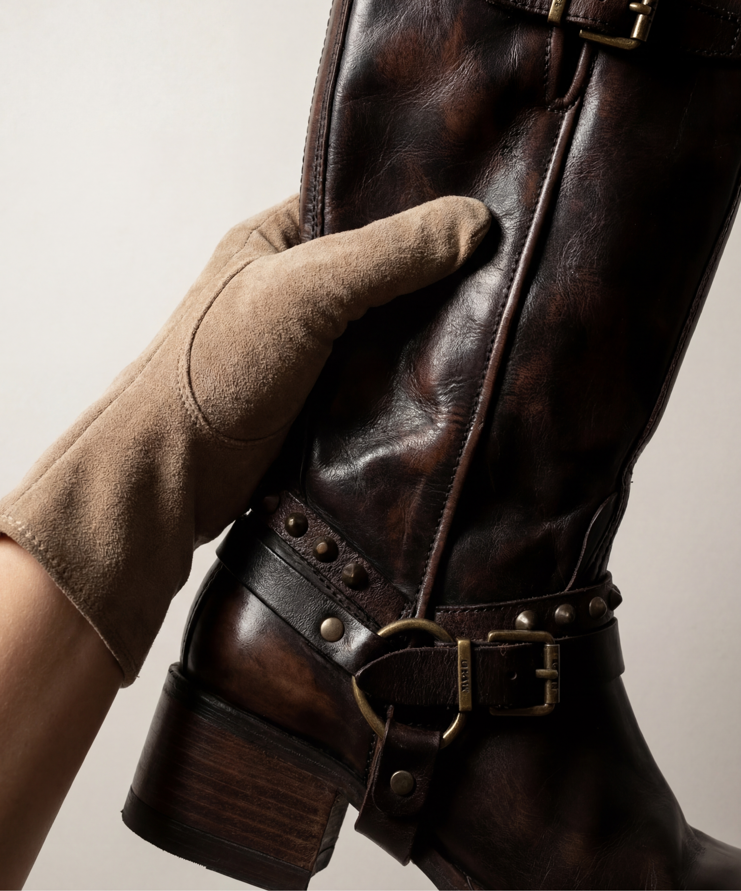 Close-up of a brown A.S.98 leather boot with stud details beside tan suede